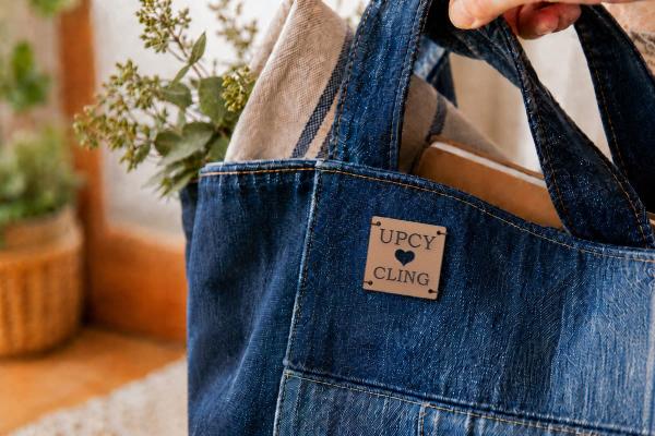Kwadratowa jasnobrązowa metka ze skóry kaktusowej z "UPCYCLING" i wyciętym sercem na torbie denim.